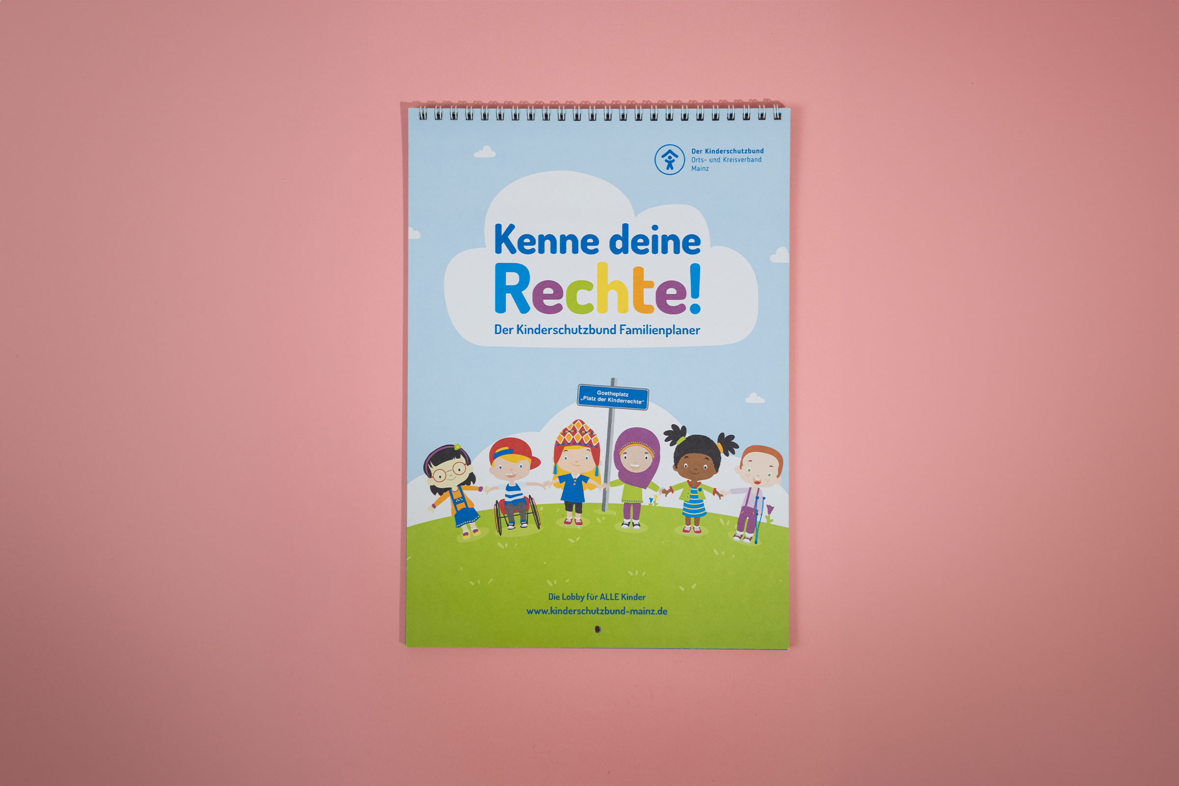 Bunter Familienplaner des Kinderschutzbundes Mainz mit dem Titel 'Kenne deine Rechte!' Fröhliche Kinder-Illustrationen und farbenfrohes Design vermitteln spielerisch wichtige Kinderrechte.