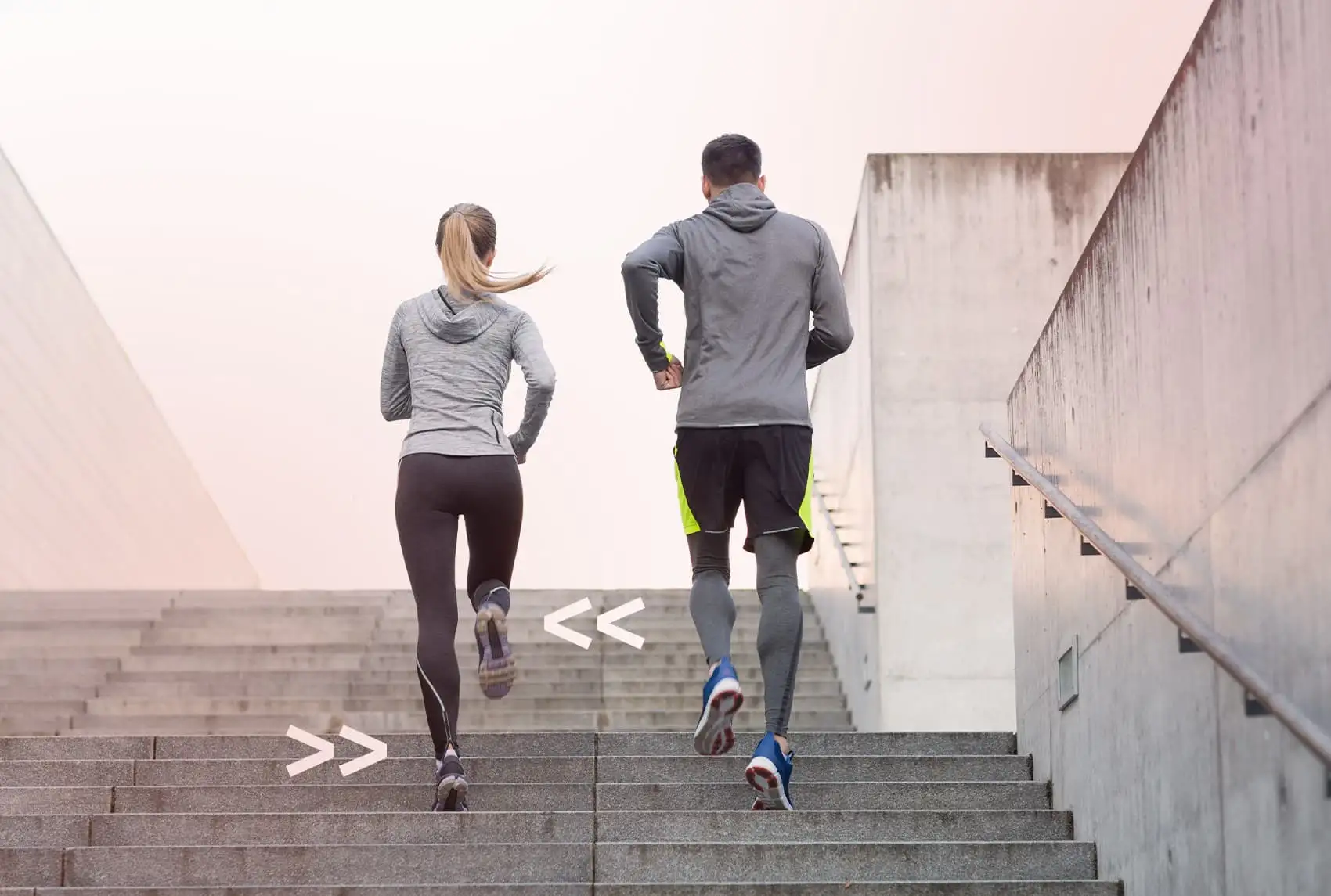 Foto von einer Läuferin und einem Läufer die die ein e Treppe hoch joggen