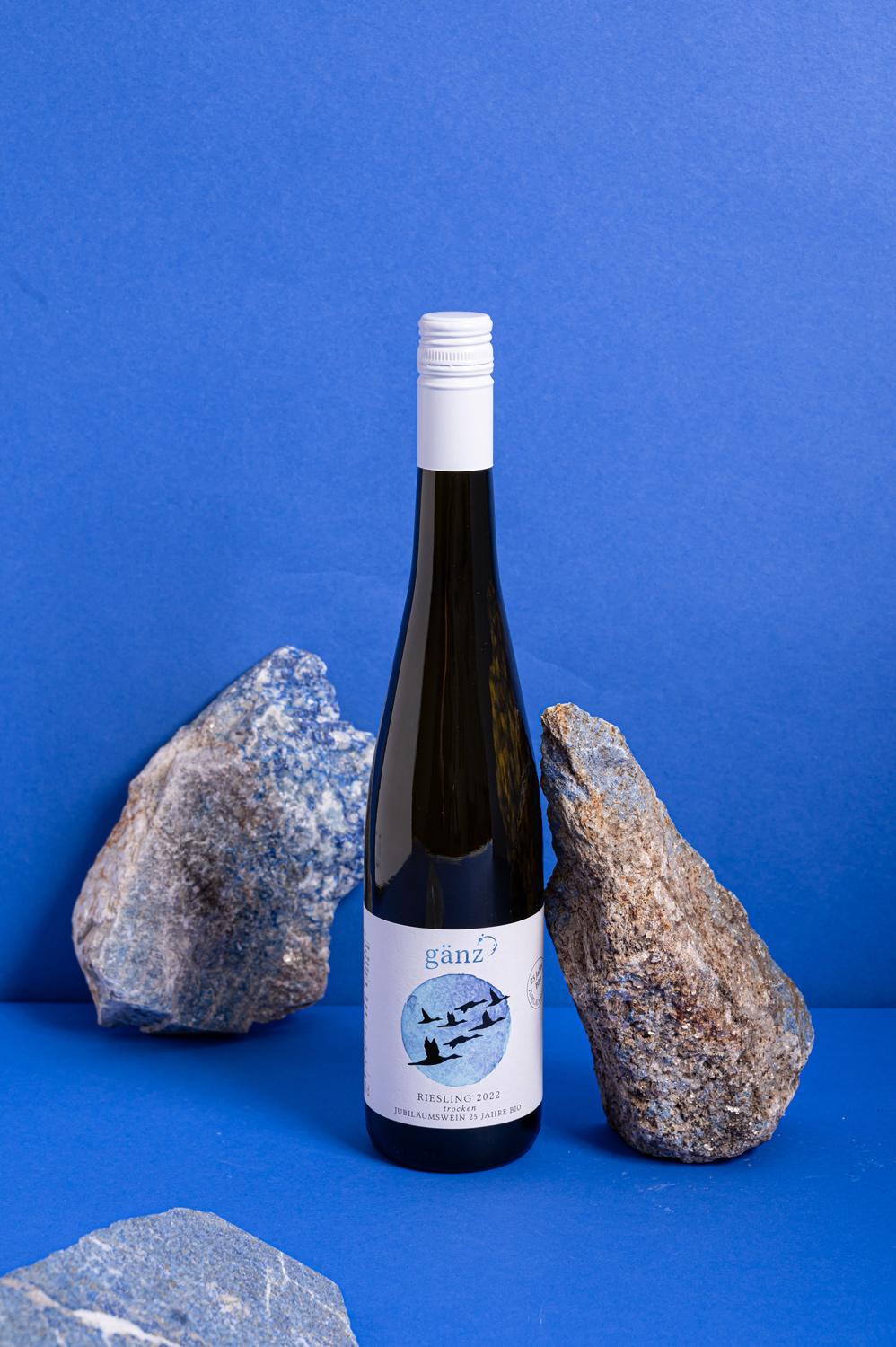 Weinflasche neben einem blauen Stein. Hintergrund ist tiefblau.